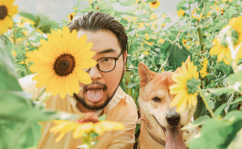 funny man and dog sticking tongues out in field of sunflowers text reads "eco-friendly pet care"