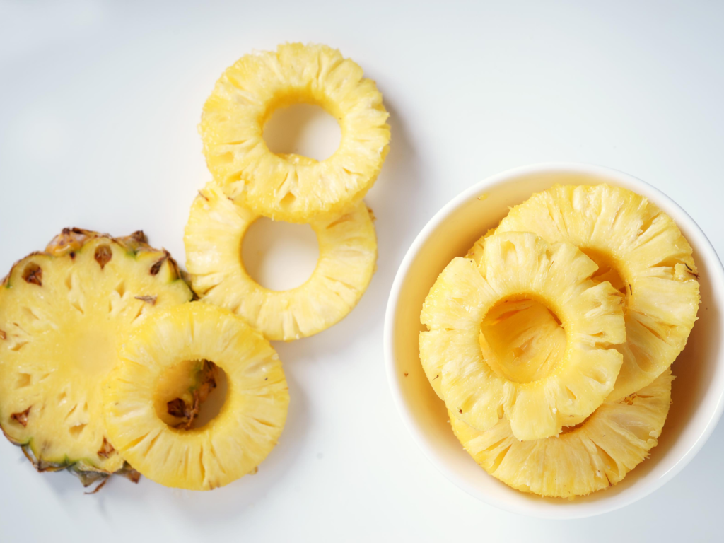sliced pineapple pieces on table and in bowl