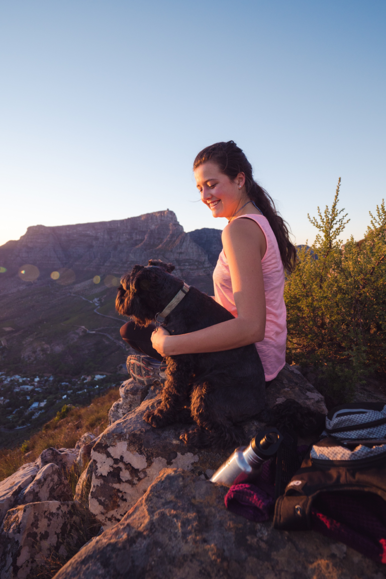 Woman with small black dog relax after a hike