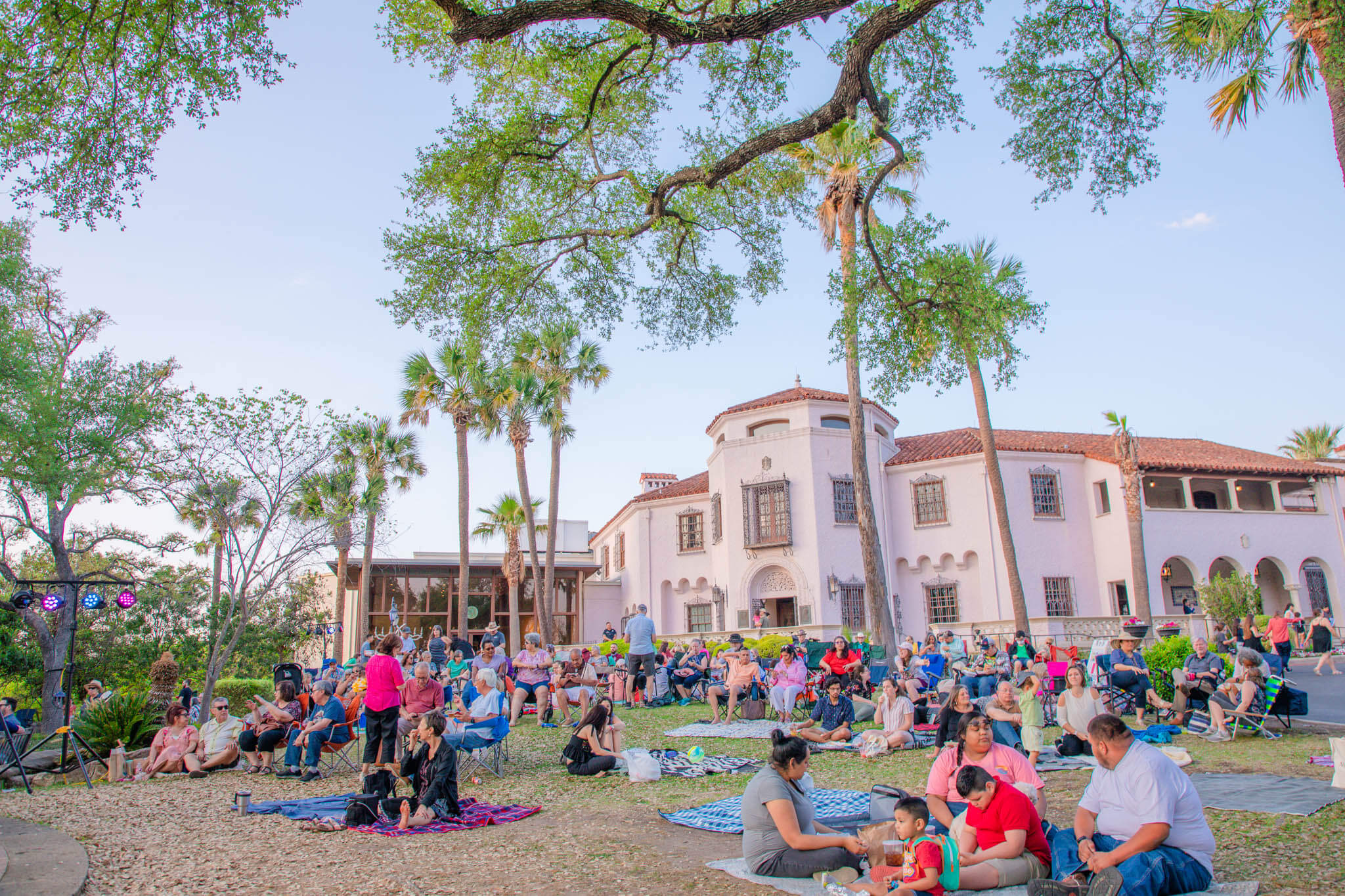 people sitting outside on picnic blankets at mcnay art museum