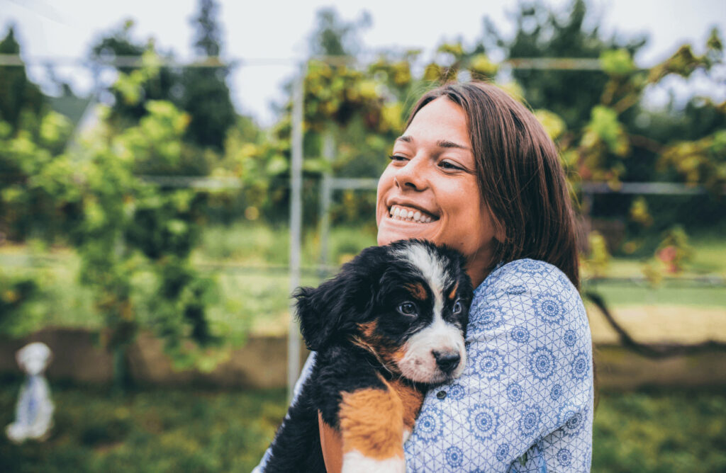 smiling woman holding puppy outside